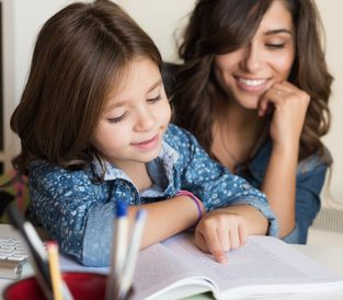 mother helping child reading book