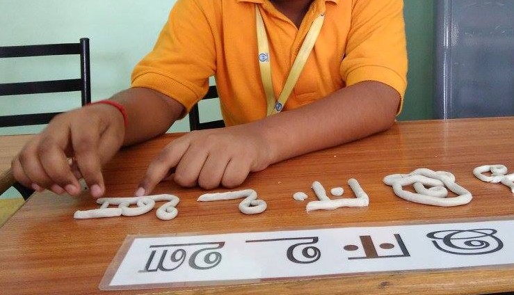 child modeling Hindi letters