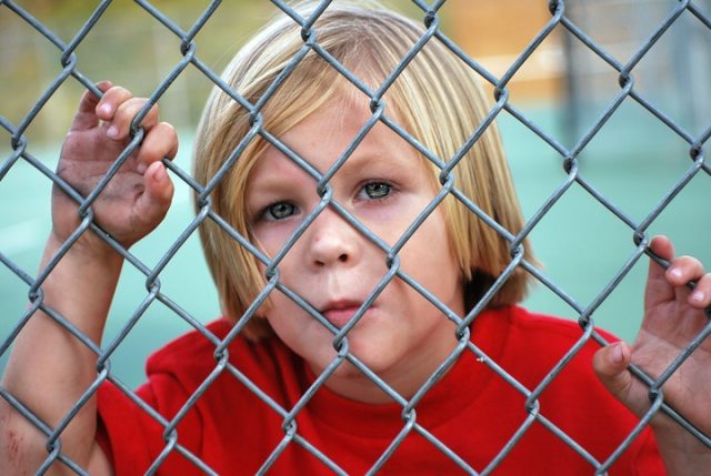 Child behind chain link fence