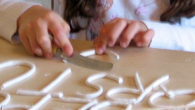child modeling clay letters