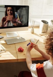 child with modeling clay in front of computer