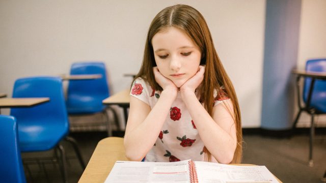 Girl with sad face in empty classroom