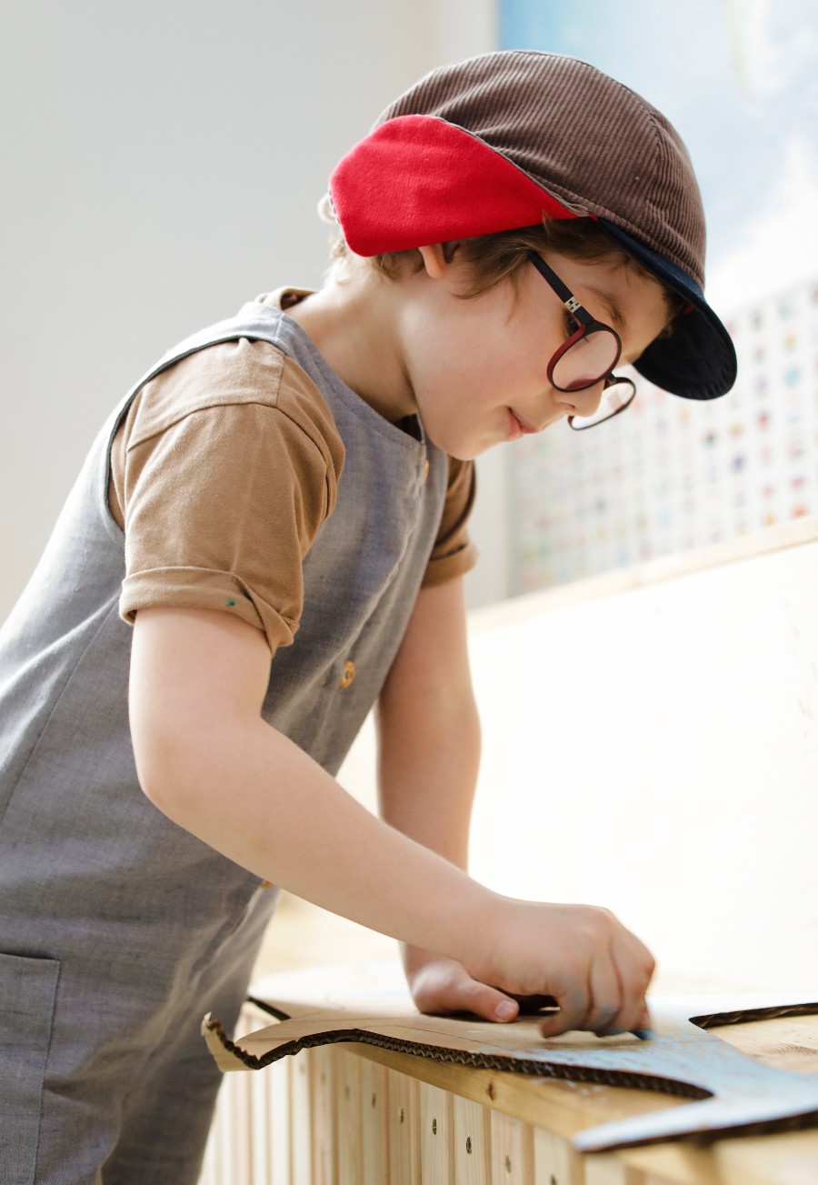 boy wearing glasses coloring a piece of cardboard