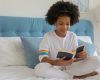 girl sitting on bed reading a book