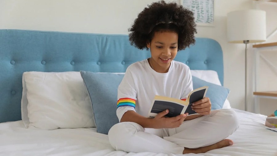 girl sitting on bed reading a book