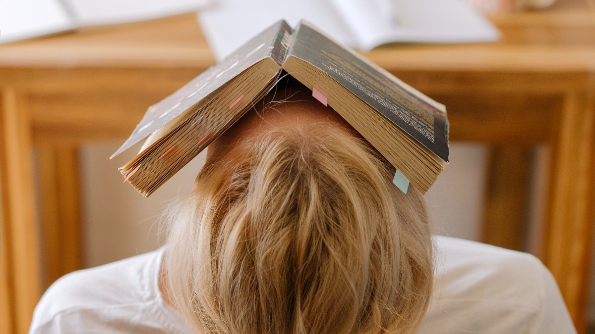 person leaning back with open book over face