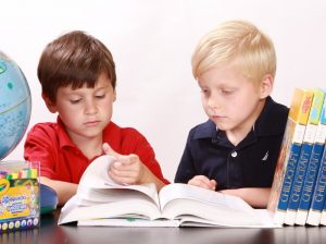 two boys sharing a reference book