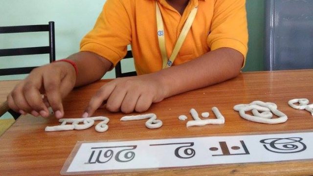 child modeling Hindi letters
